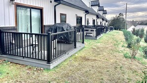 Fileira de casas brancas com grades pretas e um declive gramado.