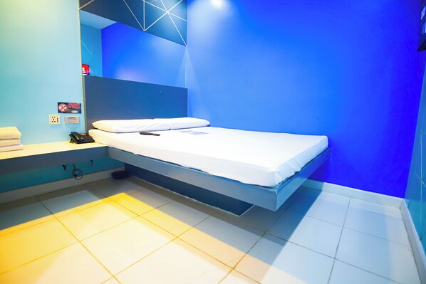 Una habitación moderna con cama, mesita de noche y teléfono en la pared.