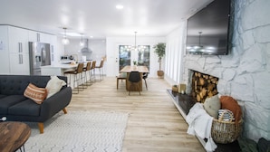 A modern kitchen with white cabinets, a built-in oven, and a dining area with a wooden table and chairs.
