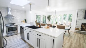 A modern kitchen with white cabinetry, stainless steel appliances, and a large island.