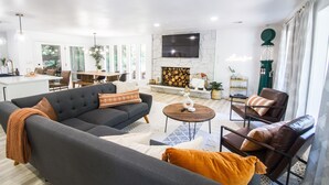 A modern living room with a fireplace, a sofa, a coffee table, and a dining area with chairs.