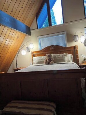 Cozy loft-style bedroom with a wooden bed and sloped ceiling.