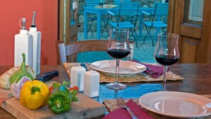 A dining table set with plates, wine glasses, and a wooden board with vegetables. - Il Bellini - Farmholiday Apartment Orciaia (Castelfranco Piandisco)