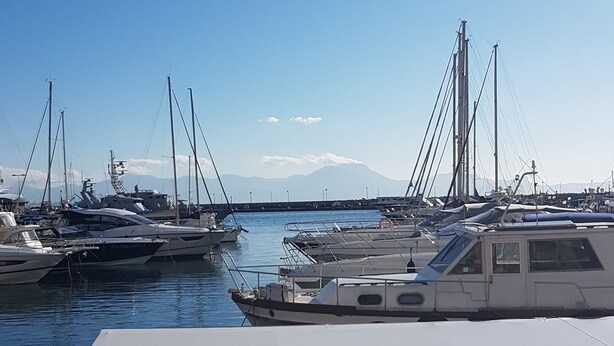A marina with multiple boats docked, a clear sky, and mountains in the background. - First House Posillipo Holiday Home Naples (Naples)