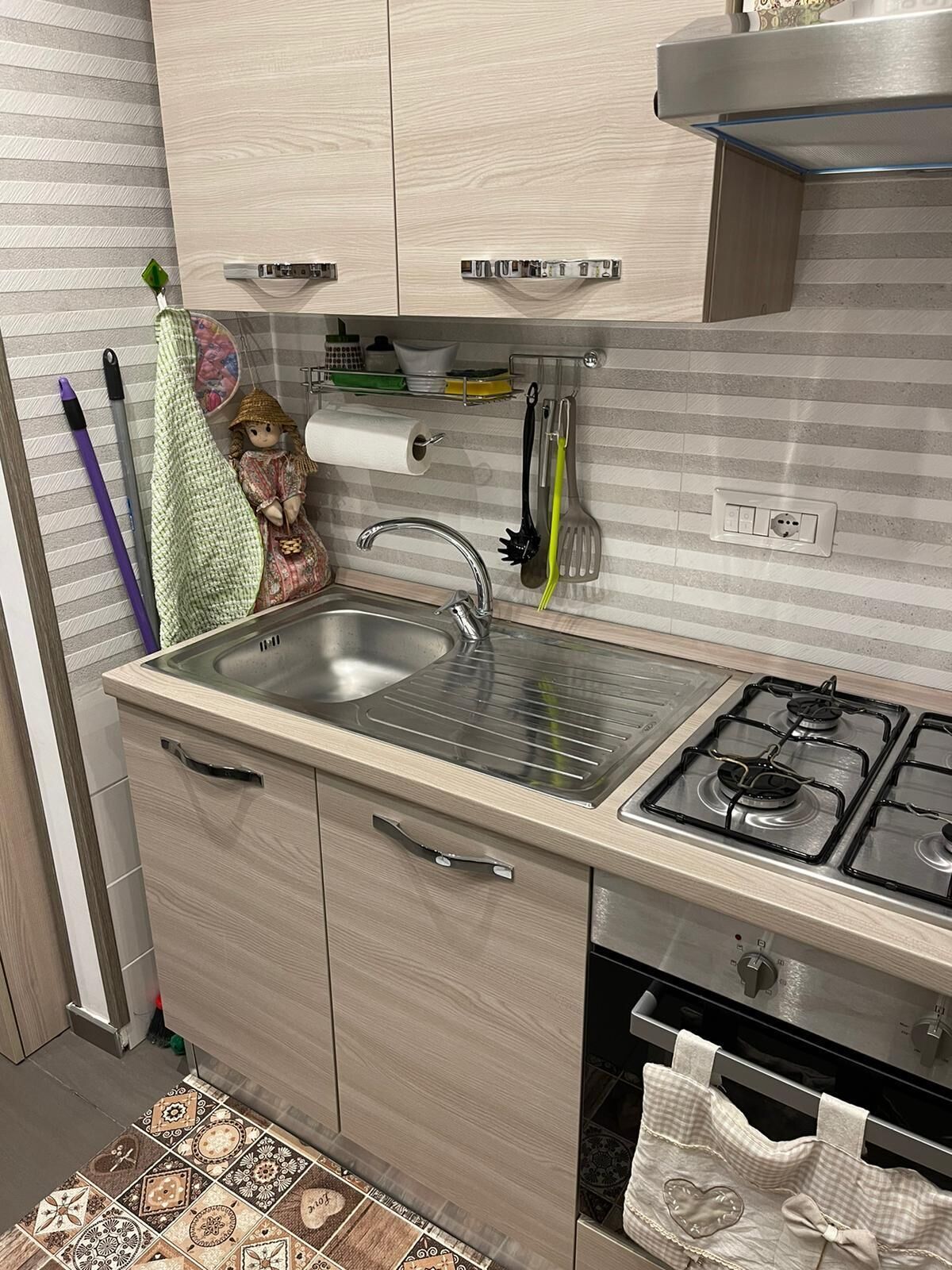 Una cocina moderna con un lavamanos de acero inoxidable, una estufa a gas y armarios de madera.
