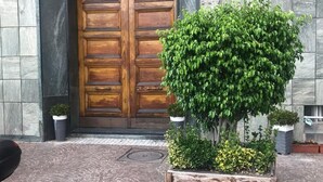 A building entrance with a wooden double door, potted plants, and a cobblestone pavement. - First House Posillipo Holiday Home Naples (Naples)