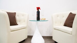 A modern room with two white sofas and a glass table with a bottle and glasses. - First House Posillipo Holiday Home Naples (Naples)