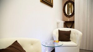 A modern living room with a white sofa, a glass coffee table, and a white armchair with a brown pillow. - First House Posillipo Holiday Home Naples (Naples)