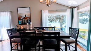 A dining area with a table, chairs, and a chandelier. There is a painting on the wall and a window with curtains. - Lake Luxury home: Elegance,Comfort,Fishing,Hunting. (Watertown)