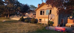 Une maison à deux étages avec une terrasse à l’avant, un panier de basketball et une antenne parabolique.