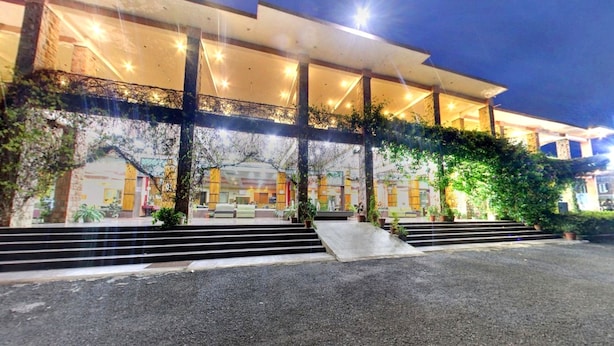 A modern building with a covered entrance, steps leading up to it, and potted plants around. - Kanthi Resorts Badami (Bagalkot)