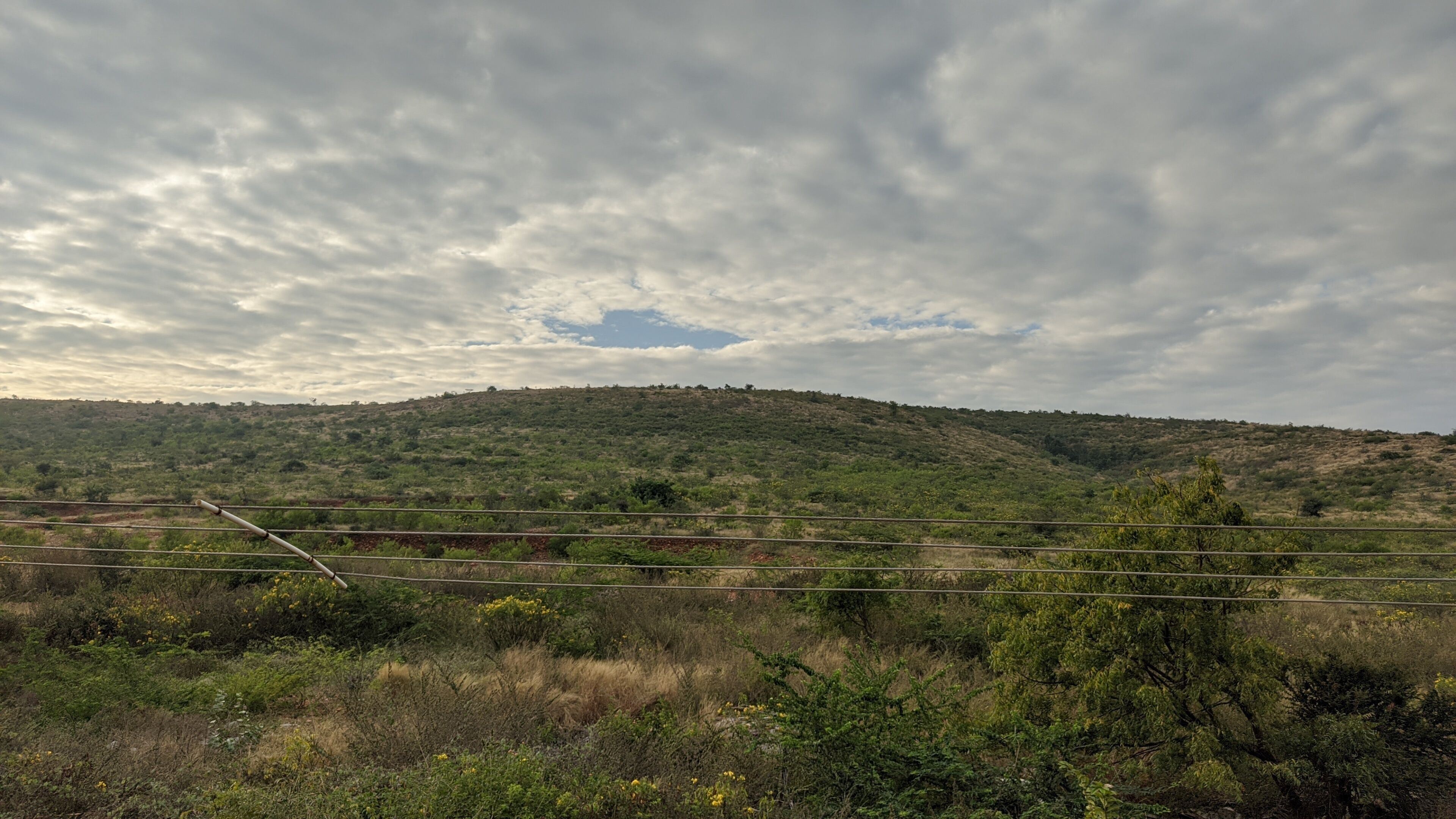 A hilly landscape with a railway track and power lines.