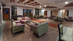 A spacious living area with multiple sofas and armchairs arranged around a central coffee table. - Kanthi Resorts Badami (Bagalkot)
