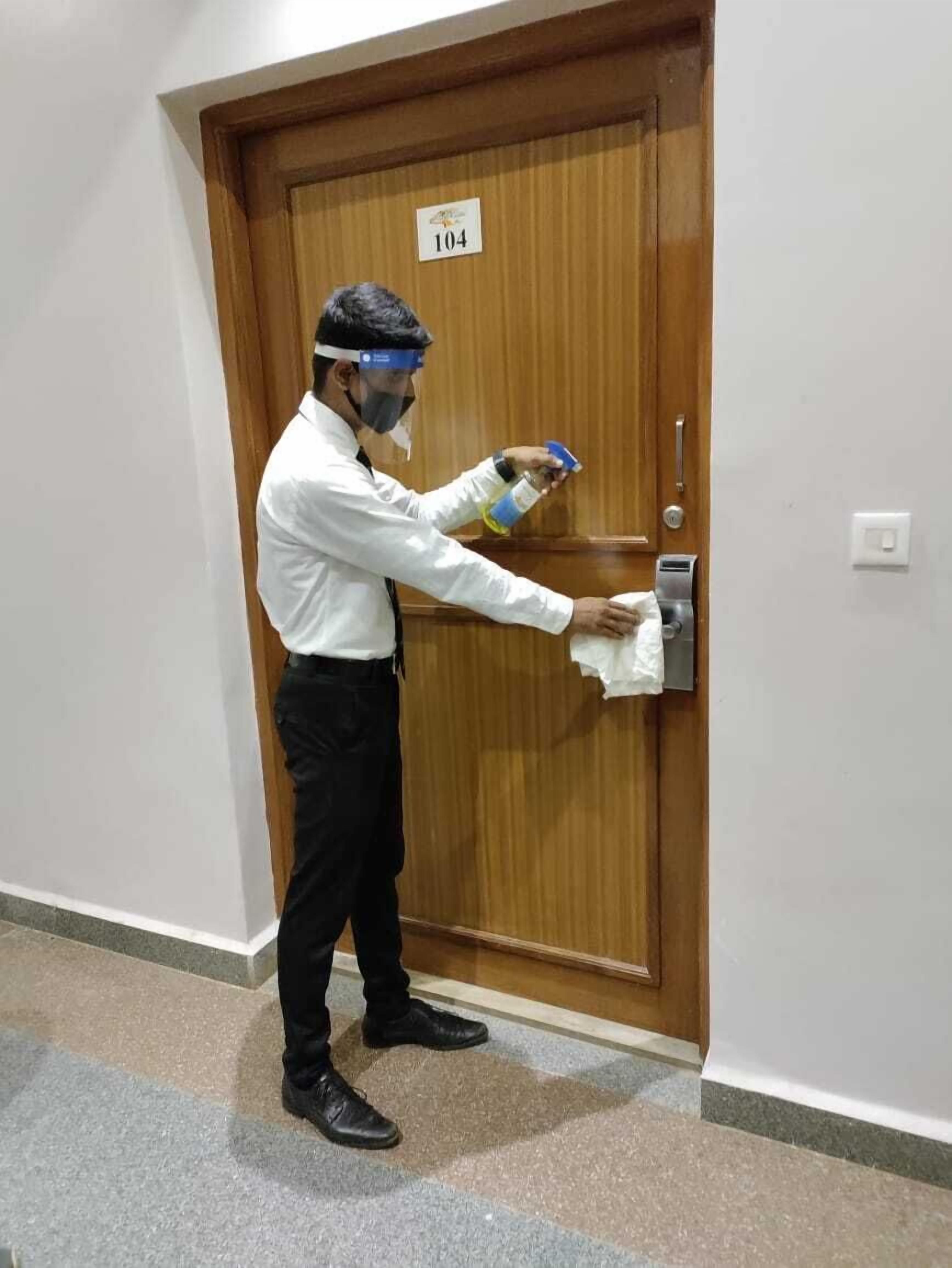 A person cleaning a door handle with a cloth.