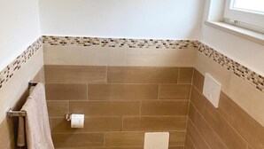A small bathroom with a toilet, bidet, and a window above the sink. - Room-the Archi B&B Apartment (Anacapri)