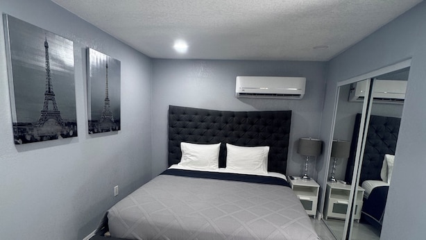 A modern bedroom with a large bed, air conditioning units, and artwork of the Eiffel Tower. - Beautiful suited with separate entrance (Las Vegas)