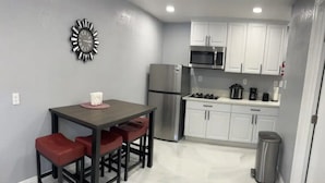 A kitchen with a stainless steel refrigerator, a microwave, and white cabinets. There is a table with red chairs and a clock on the wall. - Beautiful suited with separate entrance (Las Vegas)