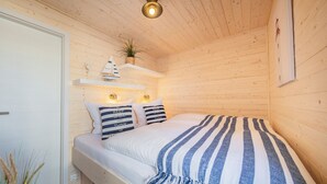 Une pièce de cabane en bois comprenant un lit, une étagère avec des objets décoratifs et une petite plante.