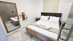 Ein modernes Hotelzimmer mit einem großen Bett, einem Nachttisch aus Holz, einer Ablage, einem Spiegel und einer kleinen Holzablage.