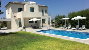 Una casa moderna de dos pisos con piscina, mobiliario exterior y césped bien cuidado.
