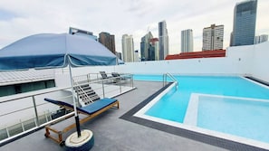 Una piscina en la azotea con el horizonte de la ciudad al fondo.