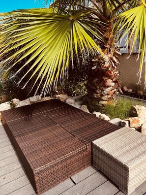A wicker outdoor seating area with a stone wall and a palm tree in the background. - Eco-Friendly Villa - 6 P - Wifi - Roquebrune Sur Argens (Roquebrune-sur-Argens)