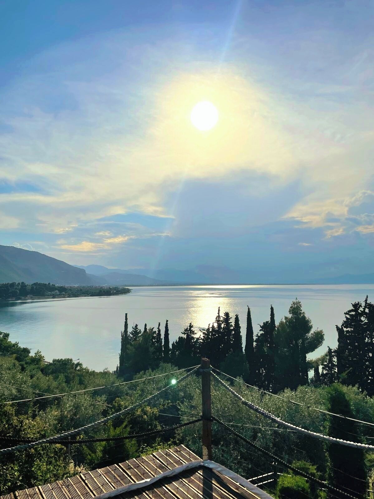 A view of a lake with mountains in the background, a wooden deck, and a rope bridge.