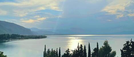 A view of a lake with mountains in the background, a wooden deck, and a rope bridge.