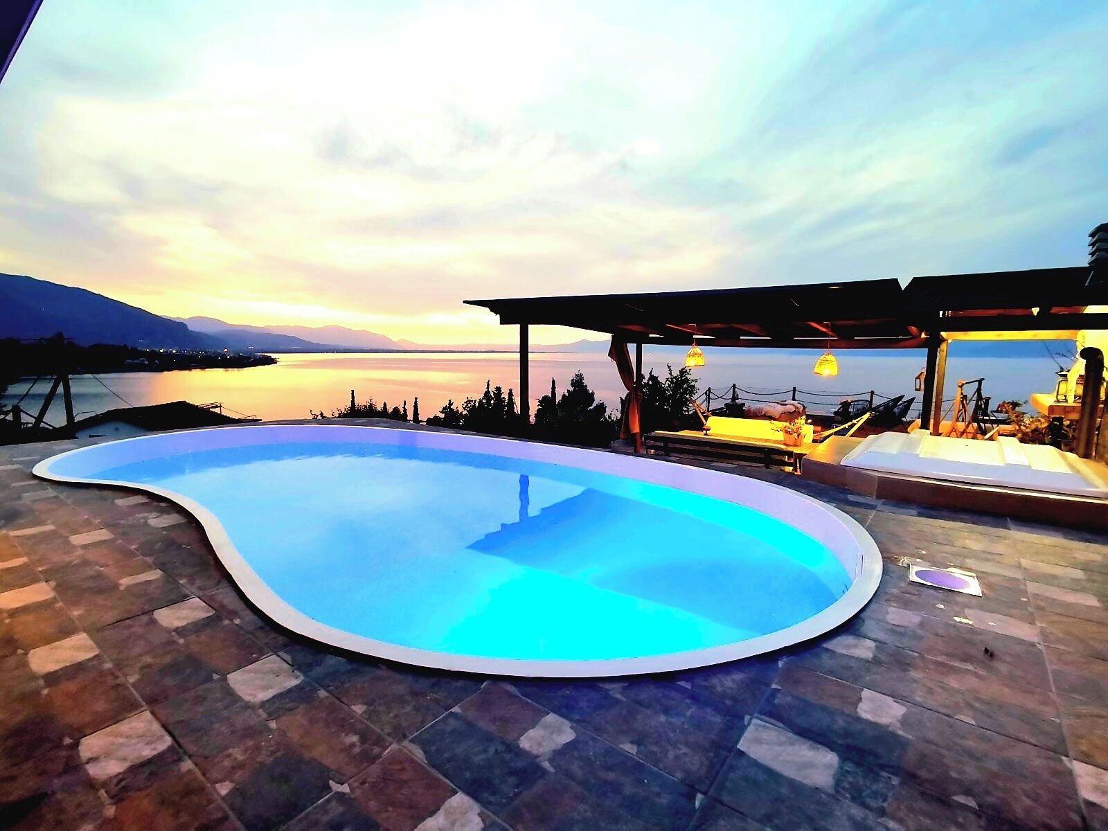 A swimming pool with a curved edge, surrounded by a stone patio.