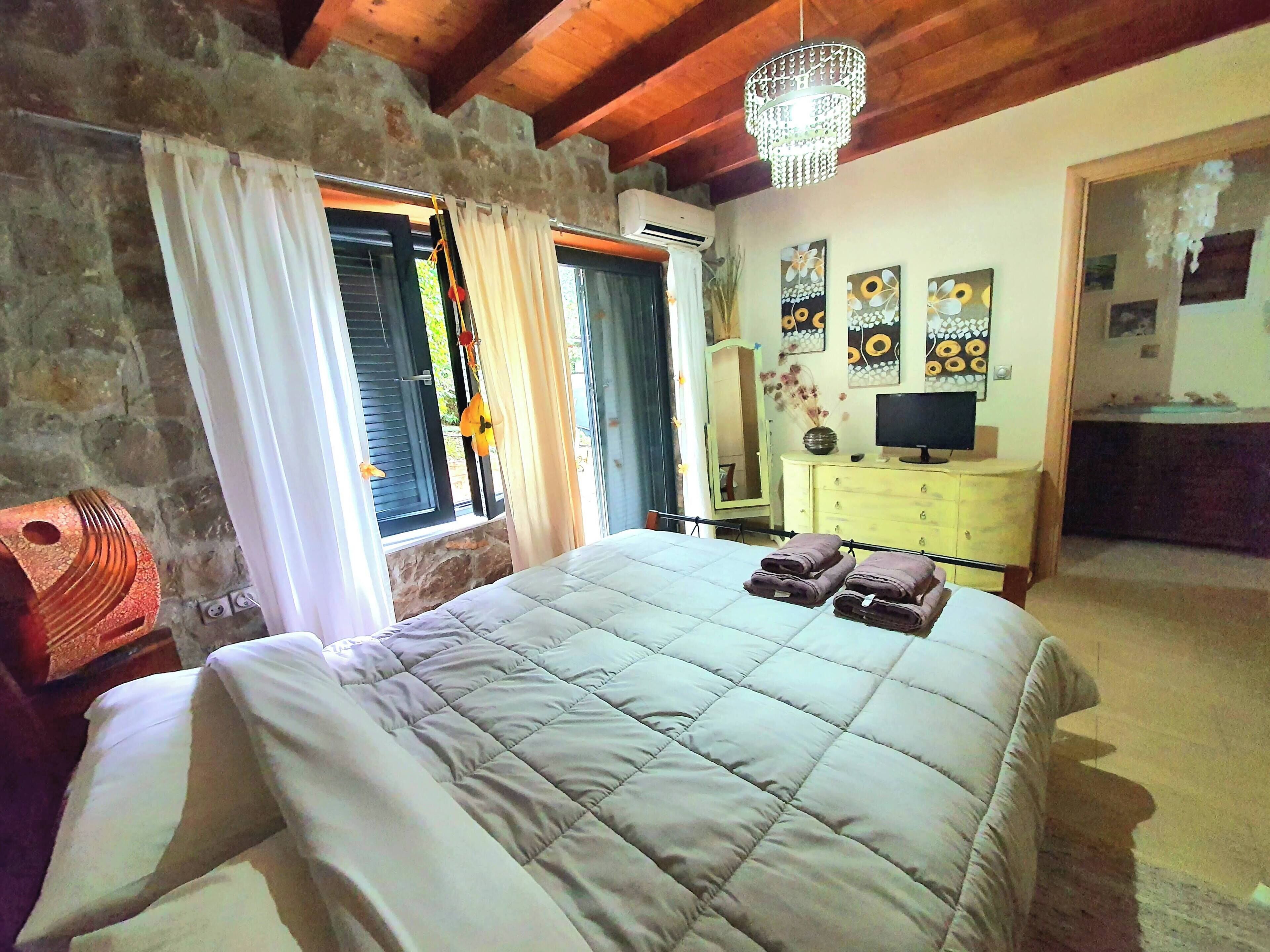 A bedroom with a bed, a dresser, a mirror, and artwork on the wall.
