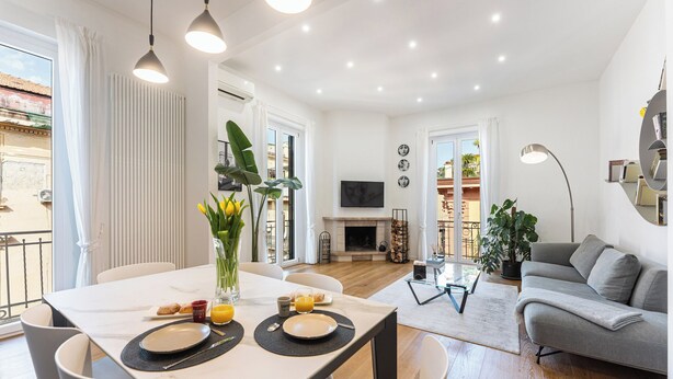 A modern living room with a sofa, a dining table set for breakfast, and a fireplace. - Terrazza San Ferdinando, Napoli (Naples)