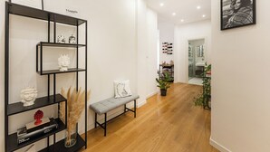 A modern interior with a wooden floor, a black metal shelf with decorative items, a bench, and a potted plant. - Terrazza San Ferdinando, Napoli (Naples)