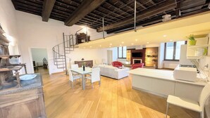 A spacious living area with a dining table, white sofas, a red chair, and a kitchen area with a modern design. - Central Spoleto 6 Guests apt With Terrace (Spoleto)