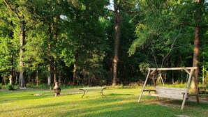 A park with a wooden swing set, a lantern, and a picnic table.