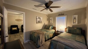 A bedroom with two beds, a ceiling fan, and a window with blinds.