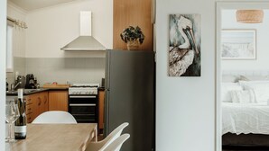 Eine moderne Küche mit weißen Schränken, einem Holzes Esstisch und einem schwarzen Kühlschrank.