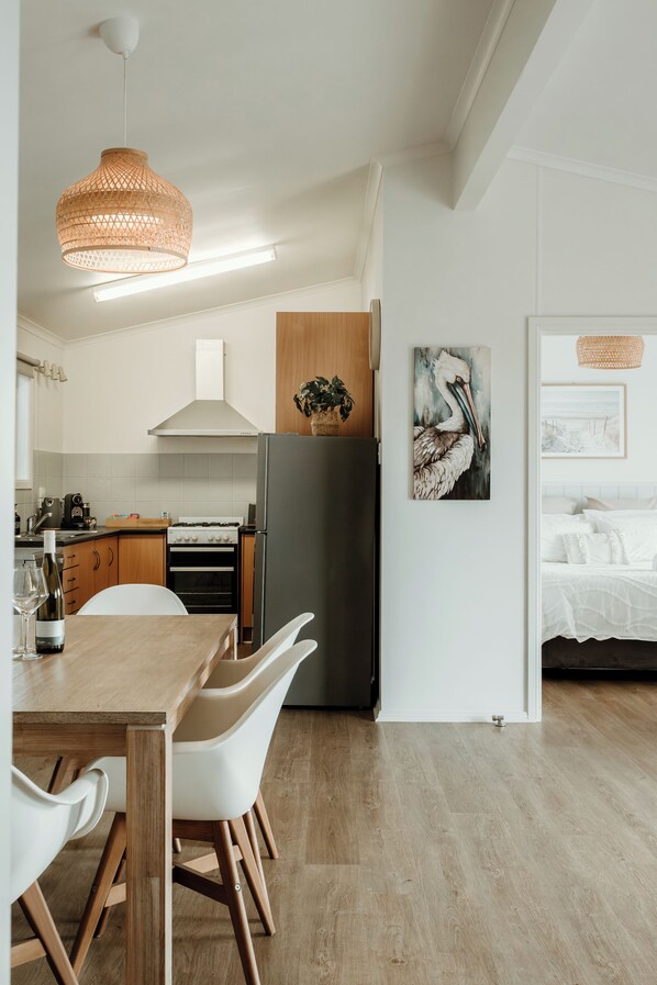 A modern kitchen with white cabinetry, a wooden dining table, and a black refrigerator. - Ki Time - in Kingscote
850m to the beach (Kingscote)