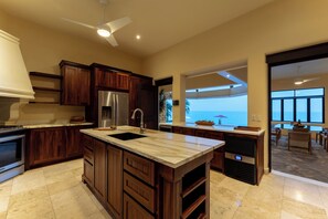 A spacious kitchen with a large island, modern appliances, and a view of the ocean.