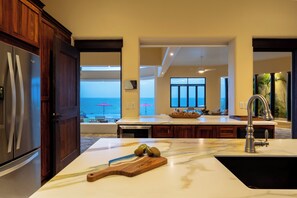 A kitchen with a large island, a view of the ocean, and a dining area with a view.