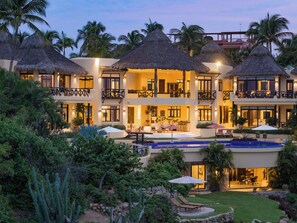 A resort with multiple thatched-roof structures, a swimming pool, and lush landscaping. - The Ultimate Indulgence (Huatulco)
