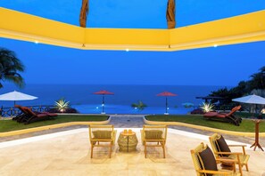 A poolside area with lounge chairs, umbrellas, and a view of the ocean. - The Ultimate Indulgence (Huatulco)