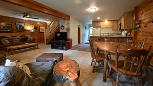 A cozy cabin interior with a wooden dining table, chairs, a sofa, and a staircase leading to an upper level. - *New Listing*|Sleeps 6| 25 Miles to Yellowstone! (Island Park)