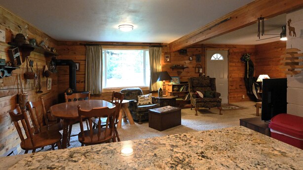 A cozy cabin interior with a wooden dining area, a fireplace, a large window, and a stone fireplace. - *New Listing*|Sleeps 6| 25 Miles to Yellowstone! (Island Park)