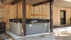 Een houten chalet met een jacuzzi onder een overdekt terras.