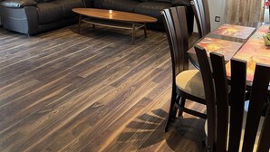 Un salon moderne avec un canapé en cuir foncé, une table basse en bois et une table à manger avec des chaises.