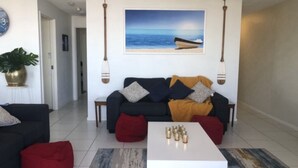Ein Wohnzimmer mit einer Couch, einem Couchtisch und einem Gemälde von einem Boot auf dem Meer.