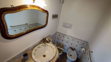 Un bagno con uno specchio grande, un lavandino, un water e un bidet.