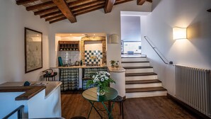 Une cuisine avec des poutres en bois, un coin repas avec une table et des chaises, et un escalier menant à l’étage.
