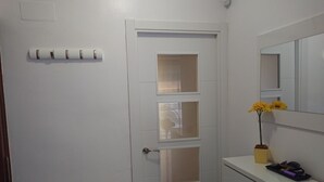 A white door with a frosted glass panel, a small mirror above it, and a yellow flower vase on a white counter.
