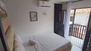 A bedroom with a bed, a wall-mounted air conditioner, and a door leading to a balcony. - Apartamento Dentro De Las Murallas De Getsemaní 3 Alcobas Con Aire Y Wifi 3cl13 (Cartagena)